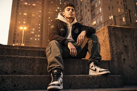 A stylish young man sitting confidently on raw concrete steps inside a dense urb - AI生成图片 3