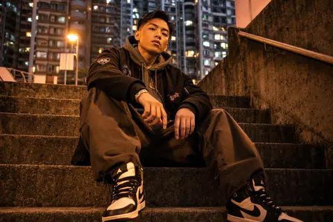 A stylish young man sitting confidently on raw concrete steps inside a dense urb - AI生成图片 1