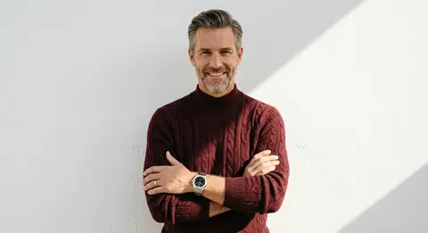 A confident gentleman smiles with arms folded in a refined studio portrait, dres - AI生成图片 1