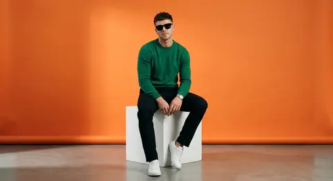A stylish fashion muse named Adrian Vale sits atop a crisp white cube in a minim - AI生成图片 1